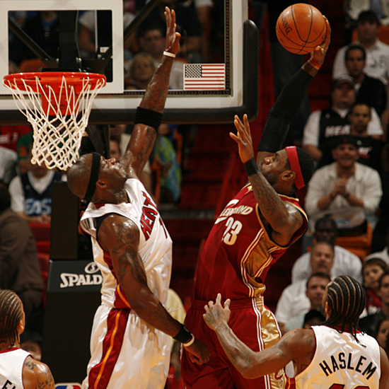 LeBron James  of the  Cleveland Cavaliers  goes  up strong to the  boards for the  dunk  over the  Miami  Heat's  Jermaine  O'Neal .   